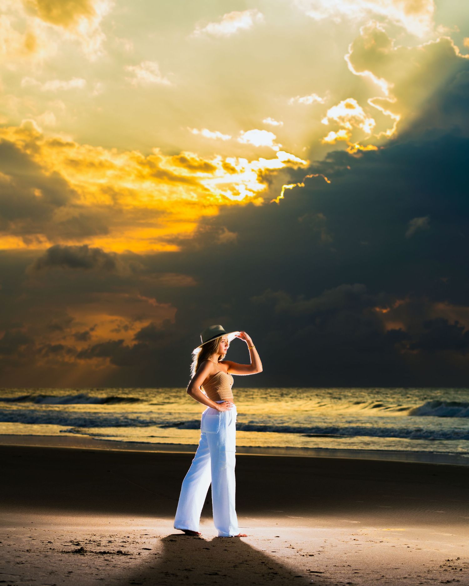 Figure in white poses on beach during dramatic golden hour sunset. Myrtle beach photographer