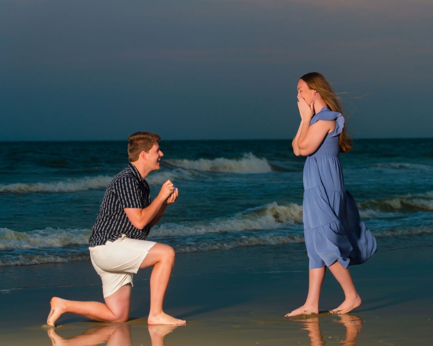 A surprise proposal scene on a beach with ocean waves in the background. Myrtle beach photographer