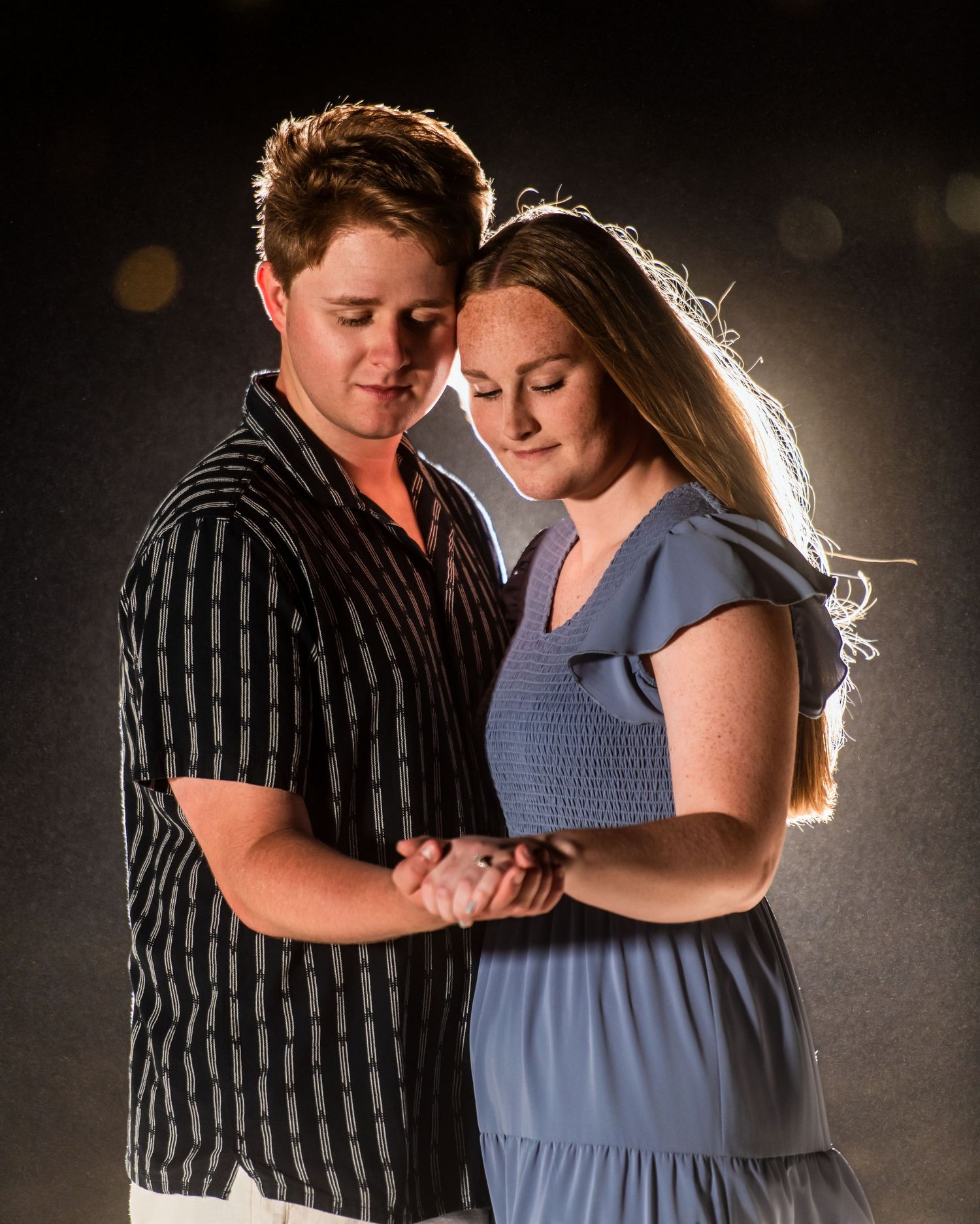 An intimate portrait of a couple backlit against a dark background. Myrtle beach photographer