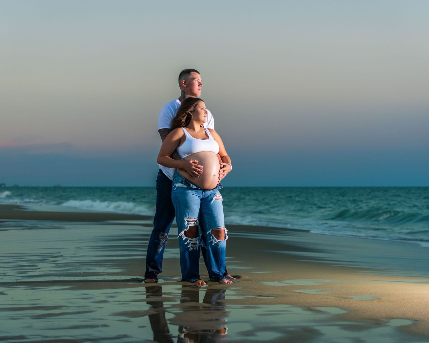 Expectant couple sharing tender moment on beach at sunset. Myrtle beach photographer