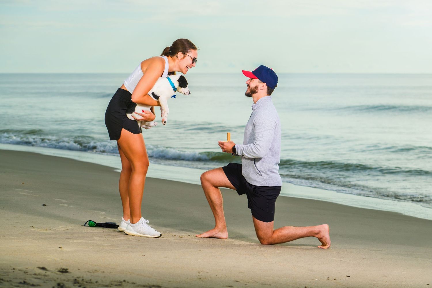 A beach proposal scene with one person kneeling in front of another by the ocean. Myrtle beach photographer