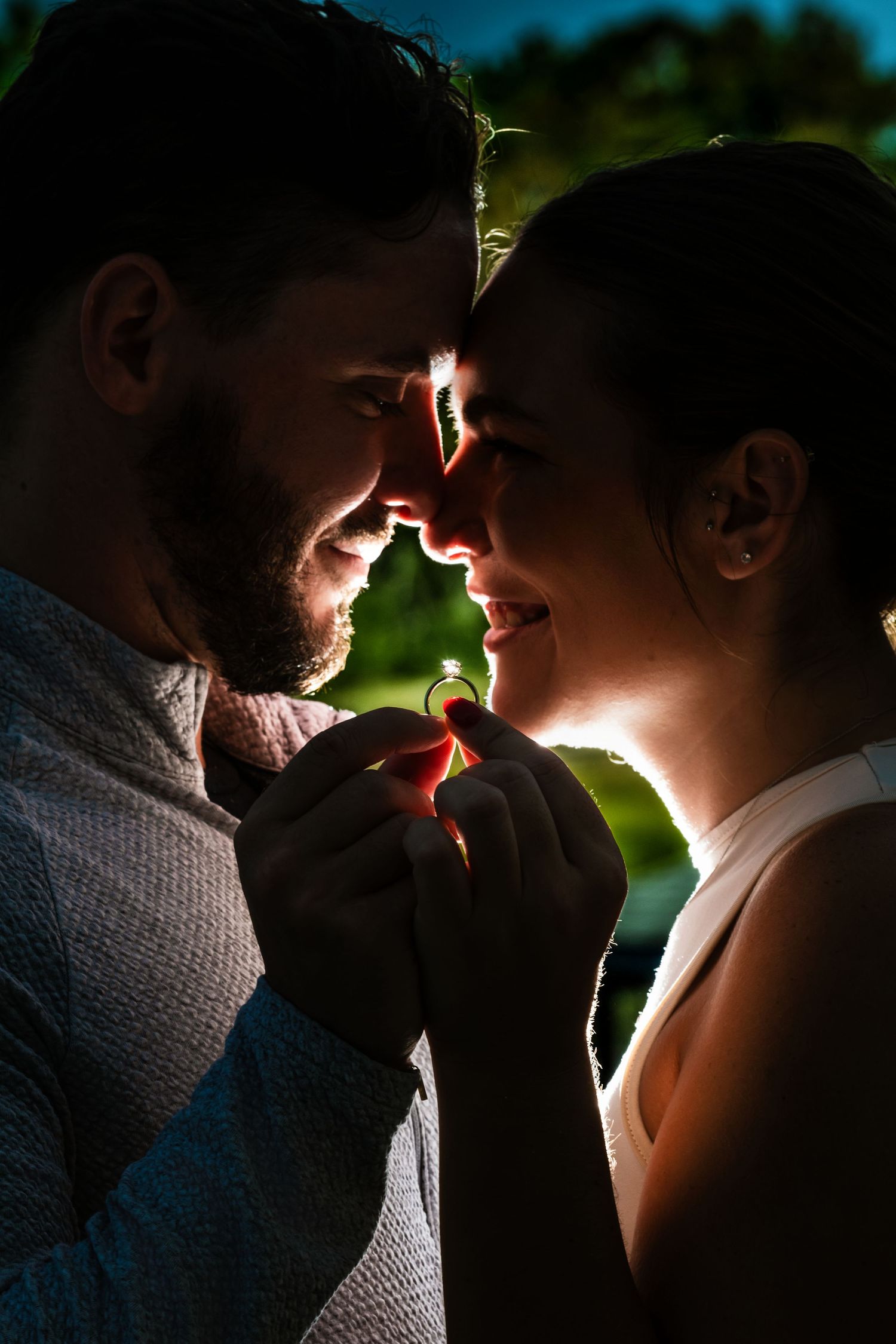 Romantic backlit silhouette of couple in intimate moment against green background. Myrtle beach photographer