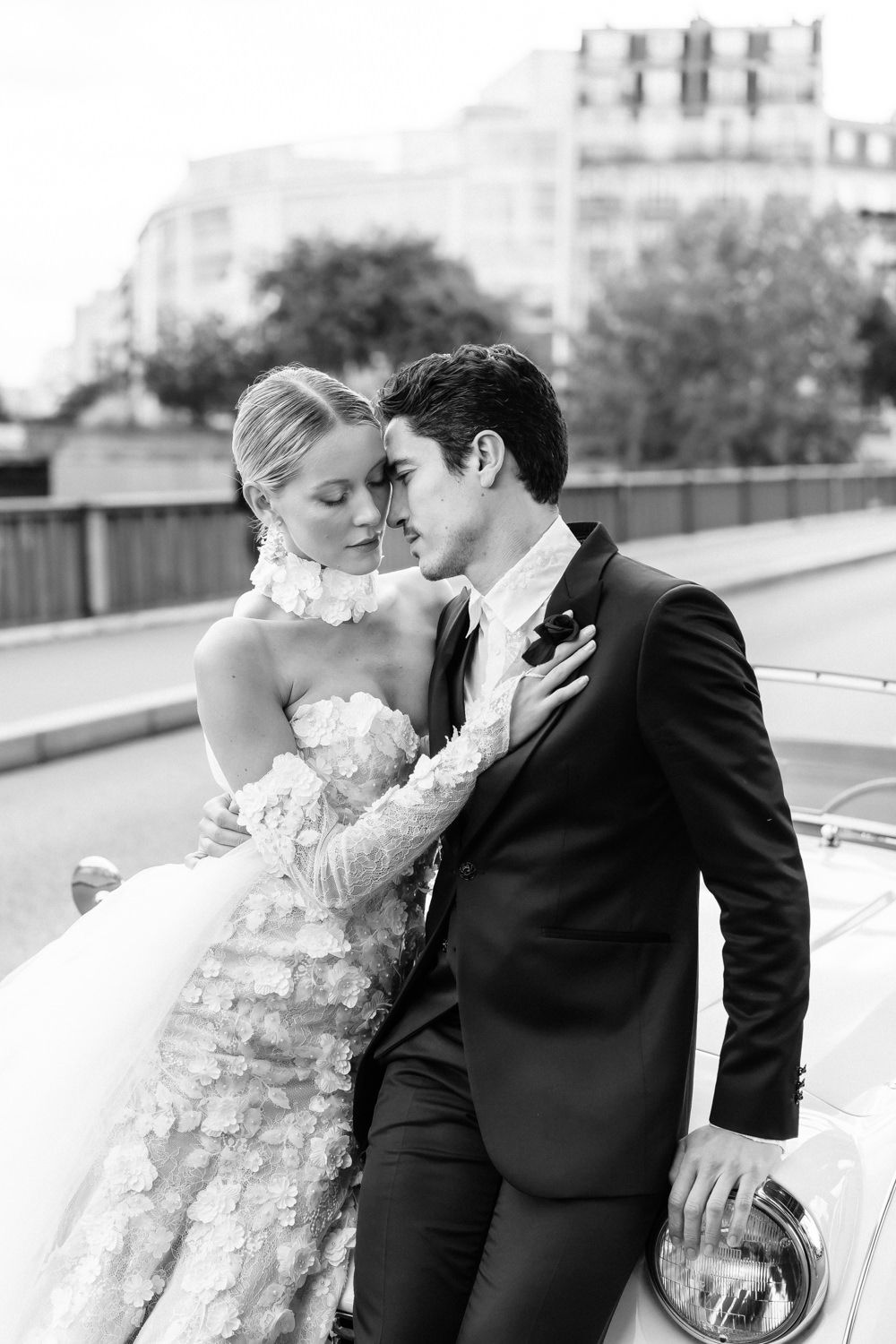 Intimate black and white portrait of couple sharing tender moment in classic car.