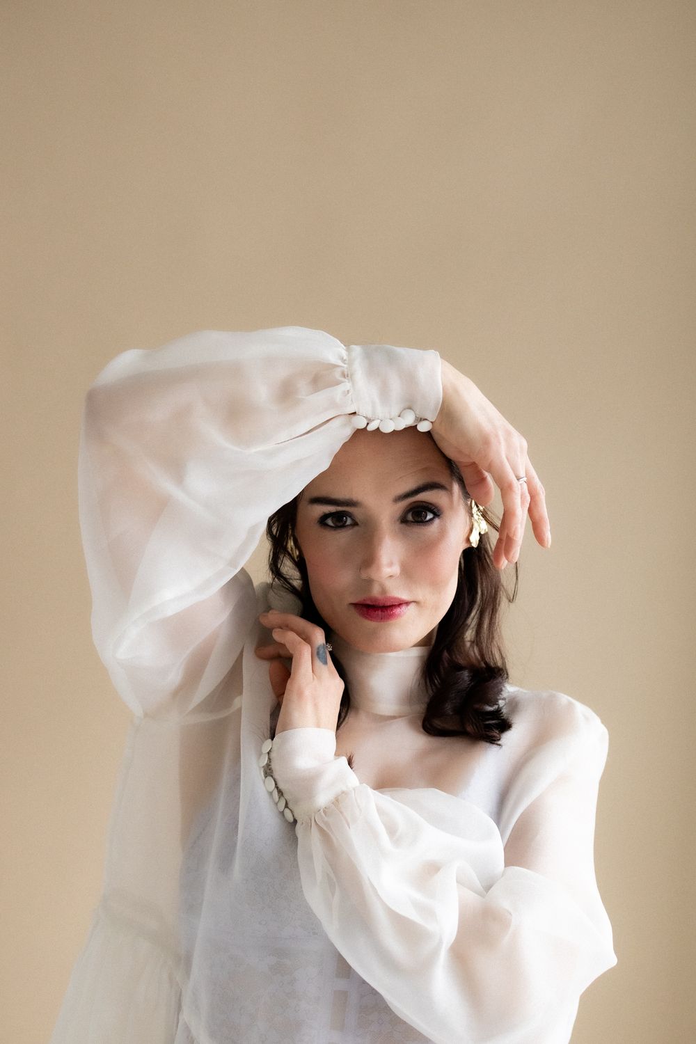 Elegant fashion photograph with flowing white fabric and soft lighting.