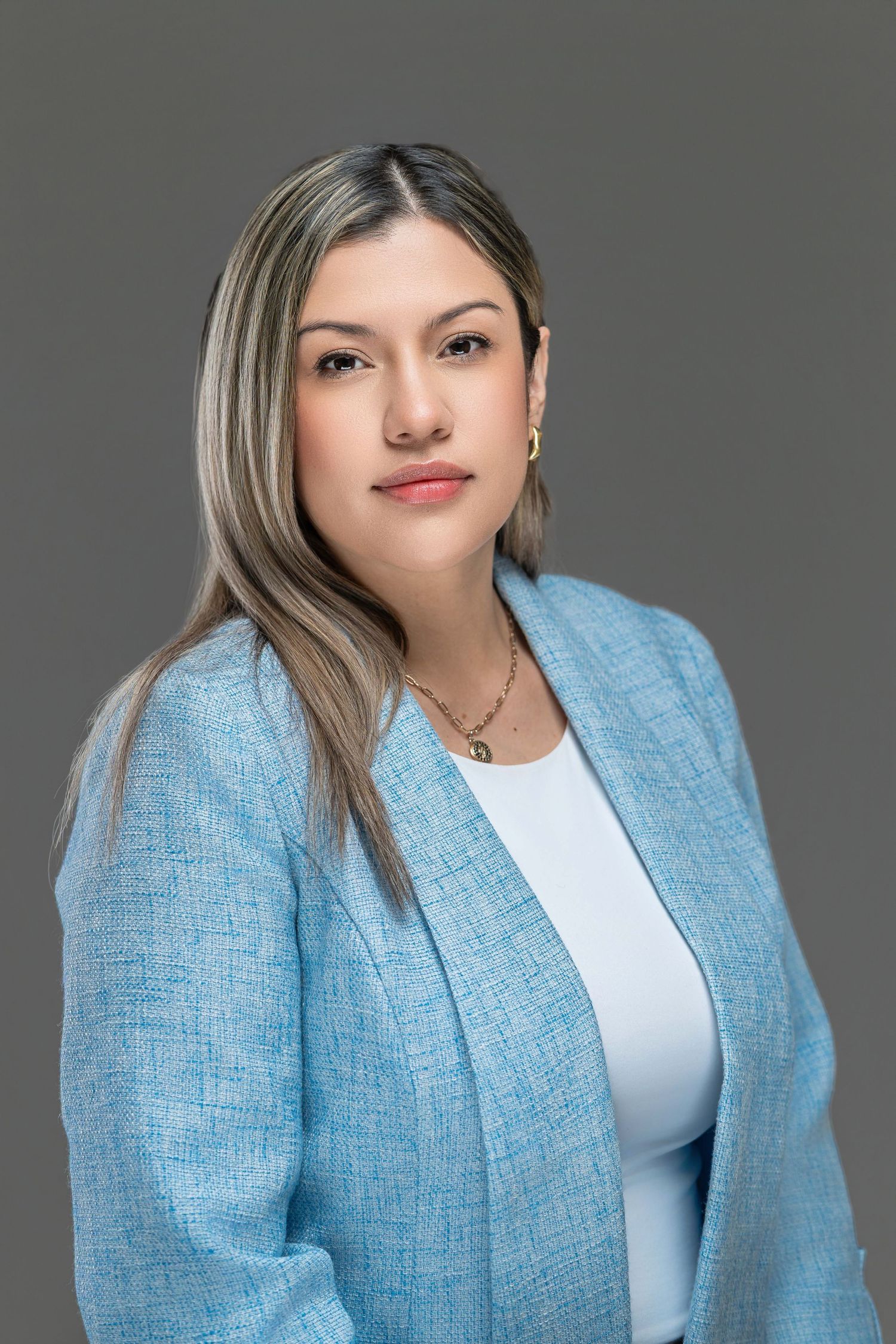 Professional headshot portrait of someone wearing a light blue blazer and white top against a gray background. Kelly Photography Atlanta.