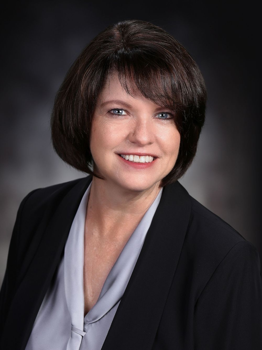 Professional headshot series showing different angles and expressions against a dark background with black blazer and white shirt.