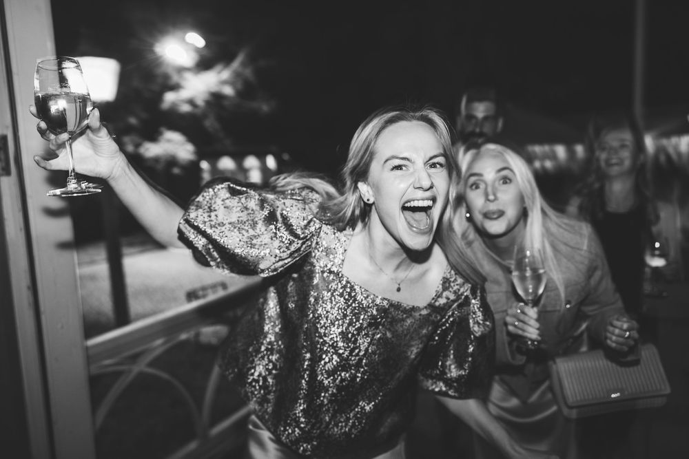 Group of party guests laughing and enjoying drinks at a nighttime celebration.