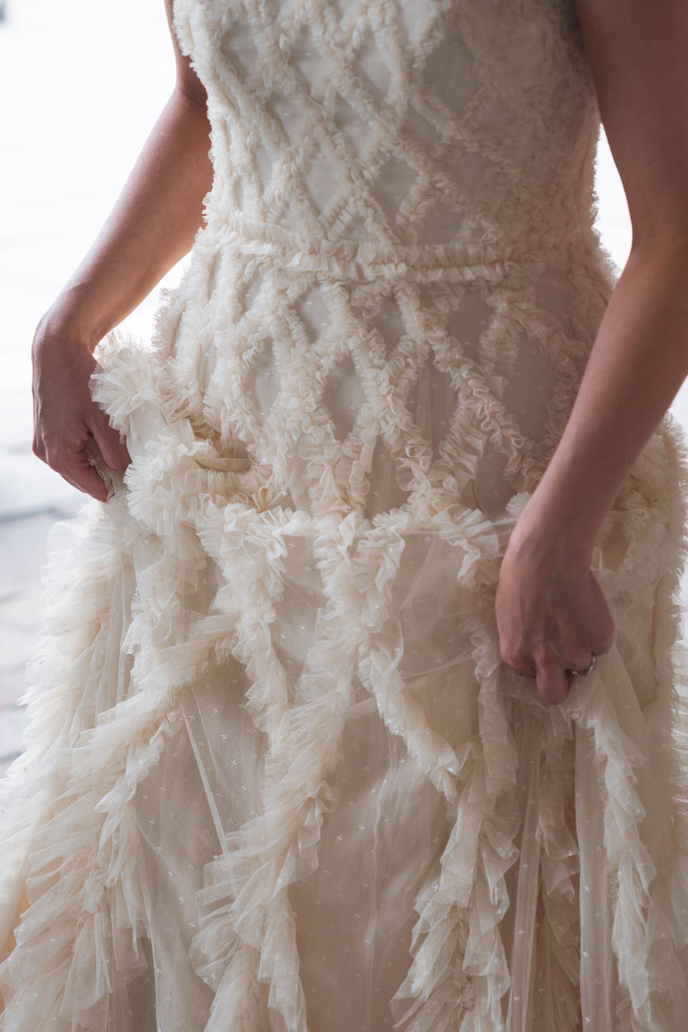 Close-up of a bride in an ivory ruffled wedding gown with diamond lattice bodice detailing.