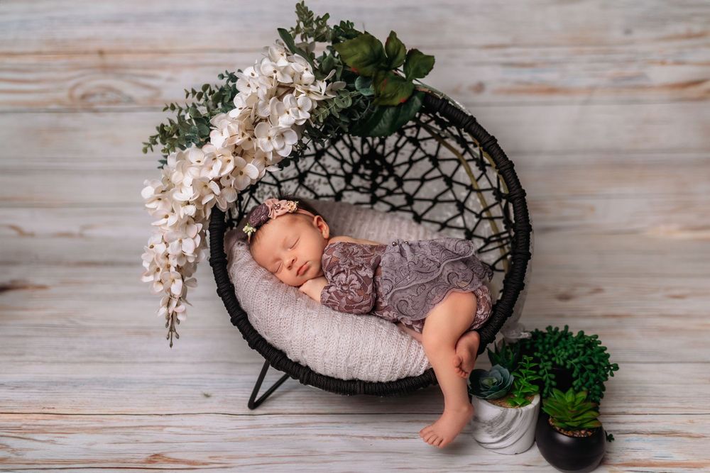 Sleeping newborn in circular nest prop with floral decorations.