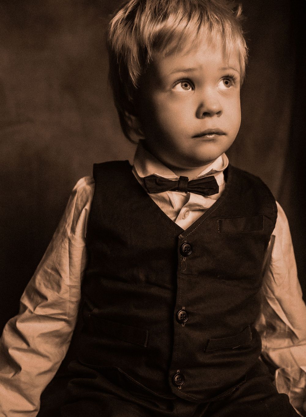 Sepia portrait of young child in formal vest and bow tie.