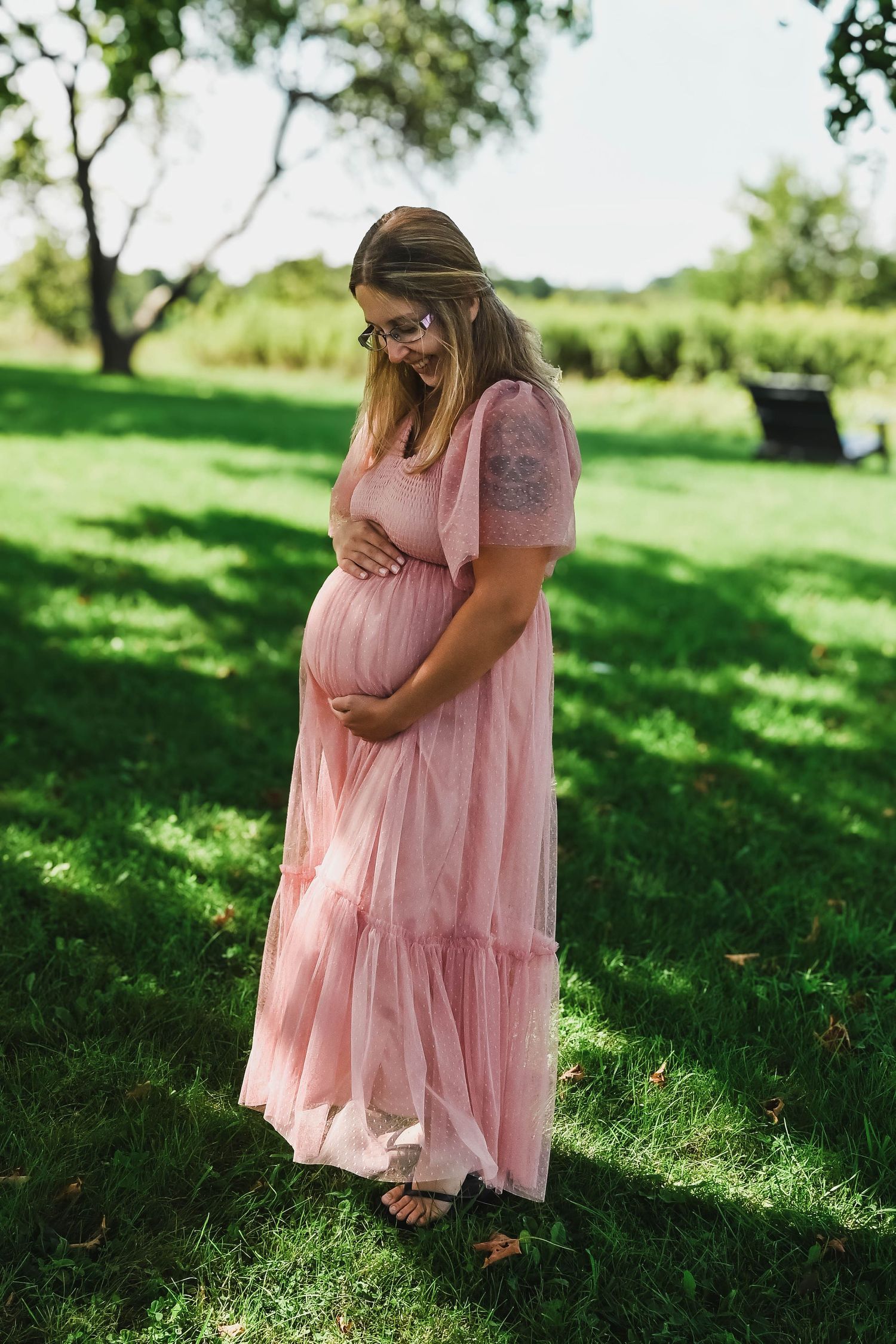 Mom looks down at her baby bump during photo shoot at Harrier Hill Park in Hudson, NY with K. Manchuck Photography