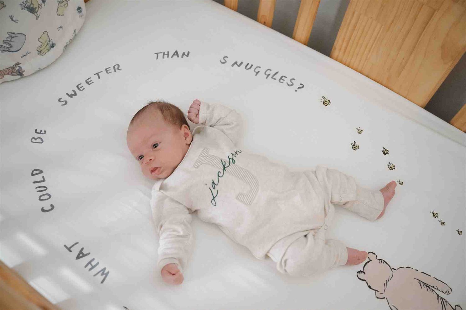 A baby rests on a personalized blanket decorated with text and delicate floral illustrations.