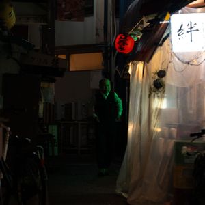 Dimly lit Japanese street market with hanging lanterns and signs.