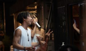 Night scene at a Japanese festival with people enjoying street food and drinks.