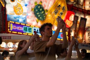 Colorful Japanese festival street scene with glowing lanterns and neon signs.