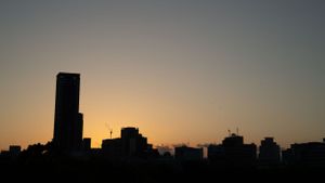 Urban skyline silhouette against an orange sunset sky.