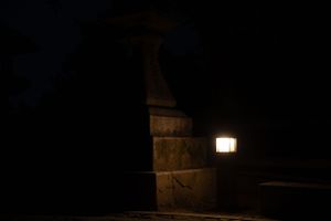 Illuminated stone lanterns glow softly in the darkness at a traditional Japanese garden.