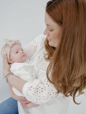 A tender moment shared between a parent and infant wearing white, with soft lighting and neutral tones.