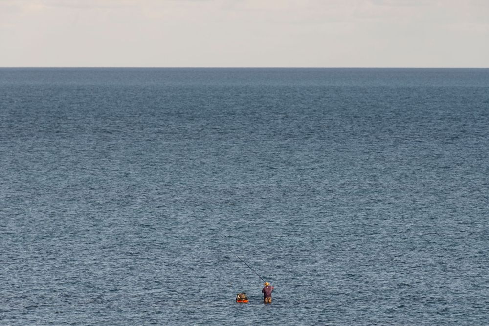 Two kayakers paddle in vast grey waters under an overcast sky.