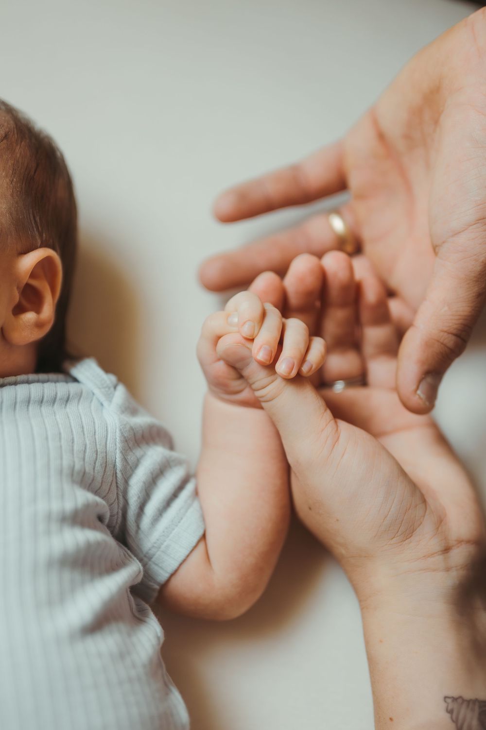 A newborn baby grasping an adult's finger, showcasing the tender bond between parent and child.