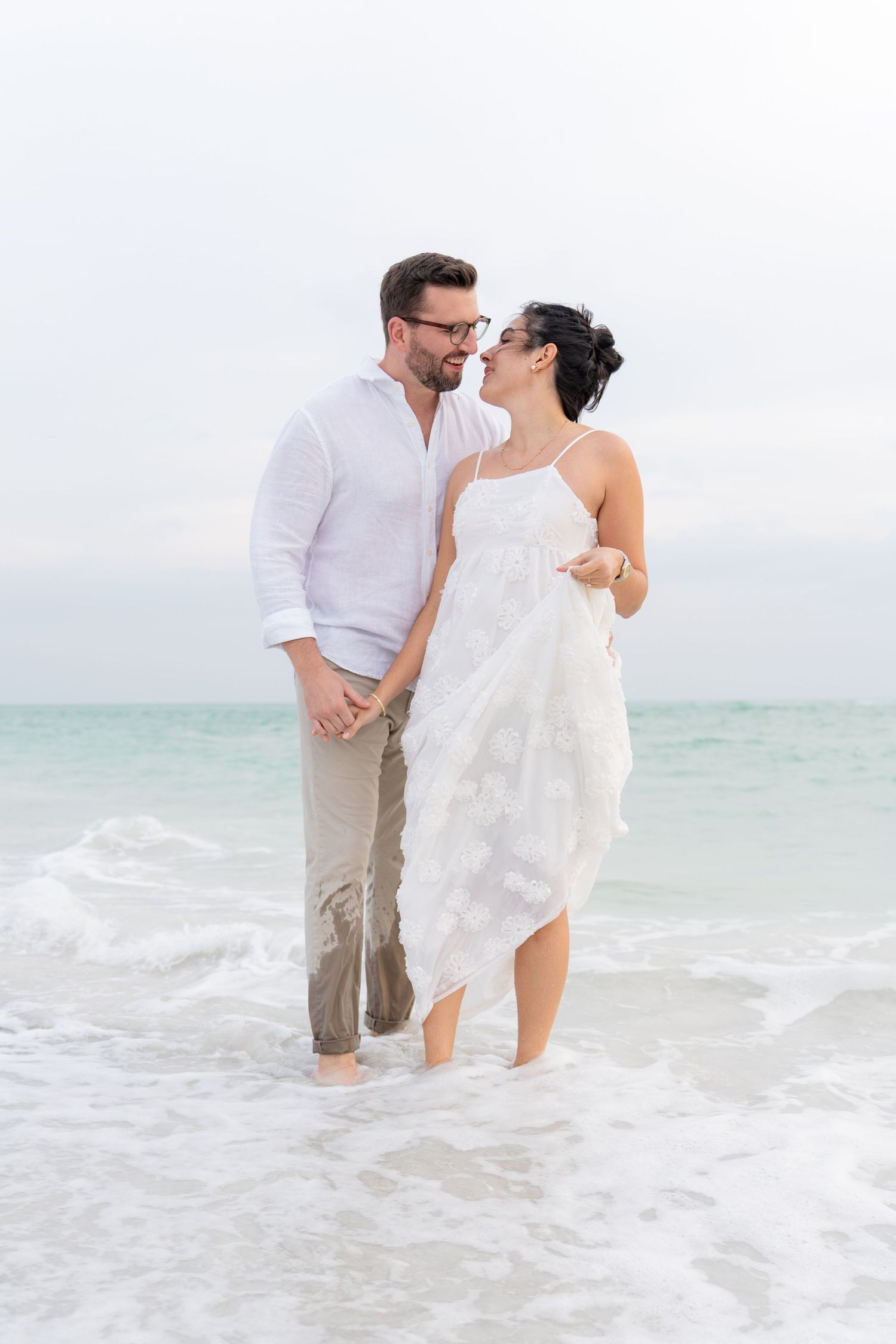 A candid moment of pure joy shared between a newly engaged couple during a beach photography session