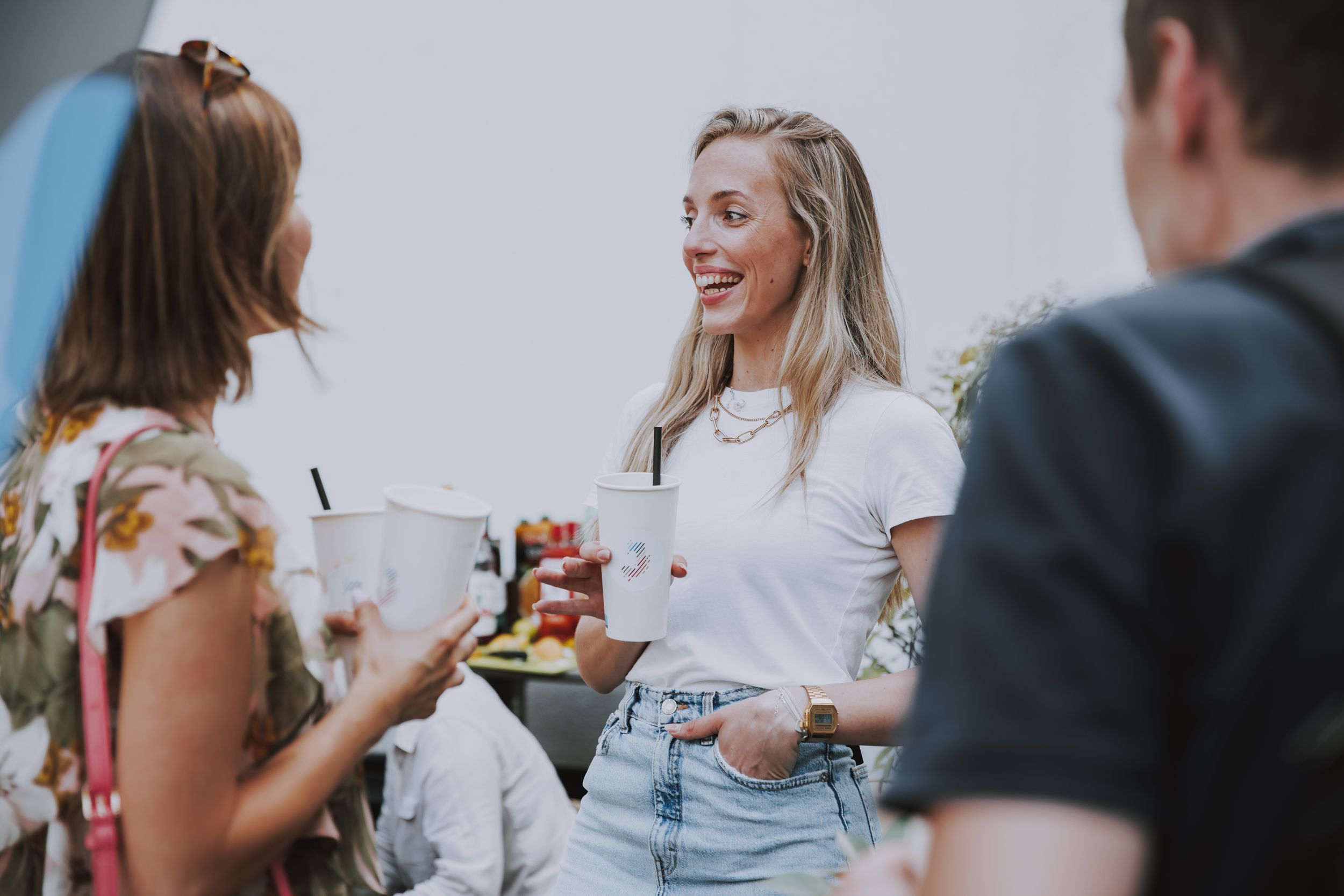 Friends sharing drinks and laughter at an outdoor social event.