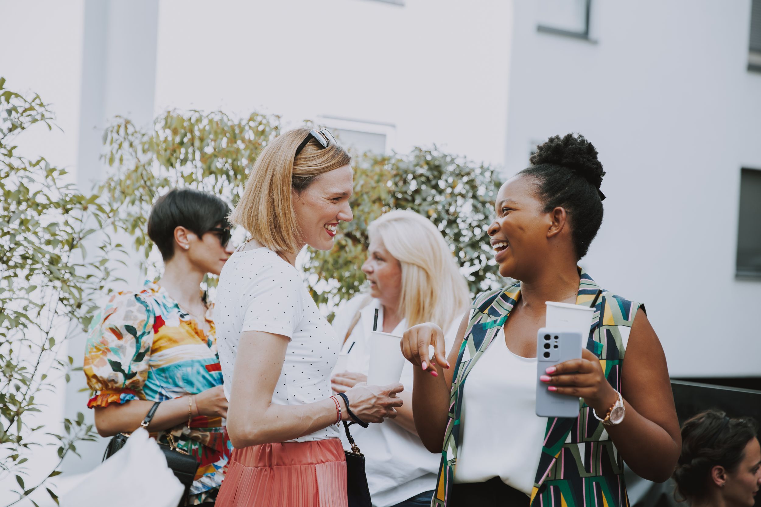 Friends enjoying beverages and conversation at outdoor social event.