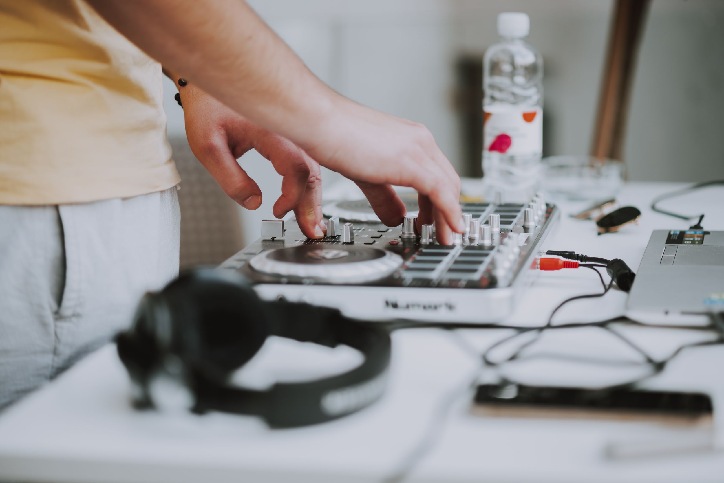 Close-up of hands operating DJ equipment with headphones in foreground.