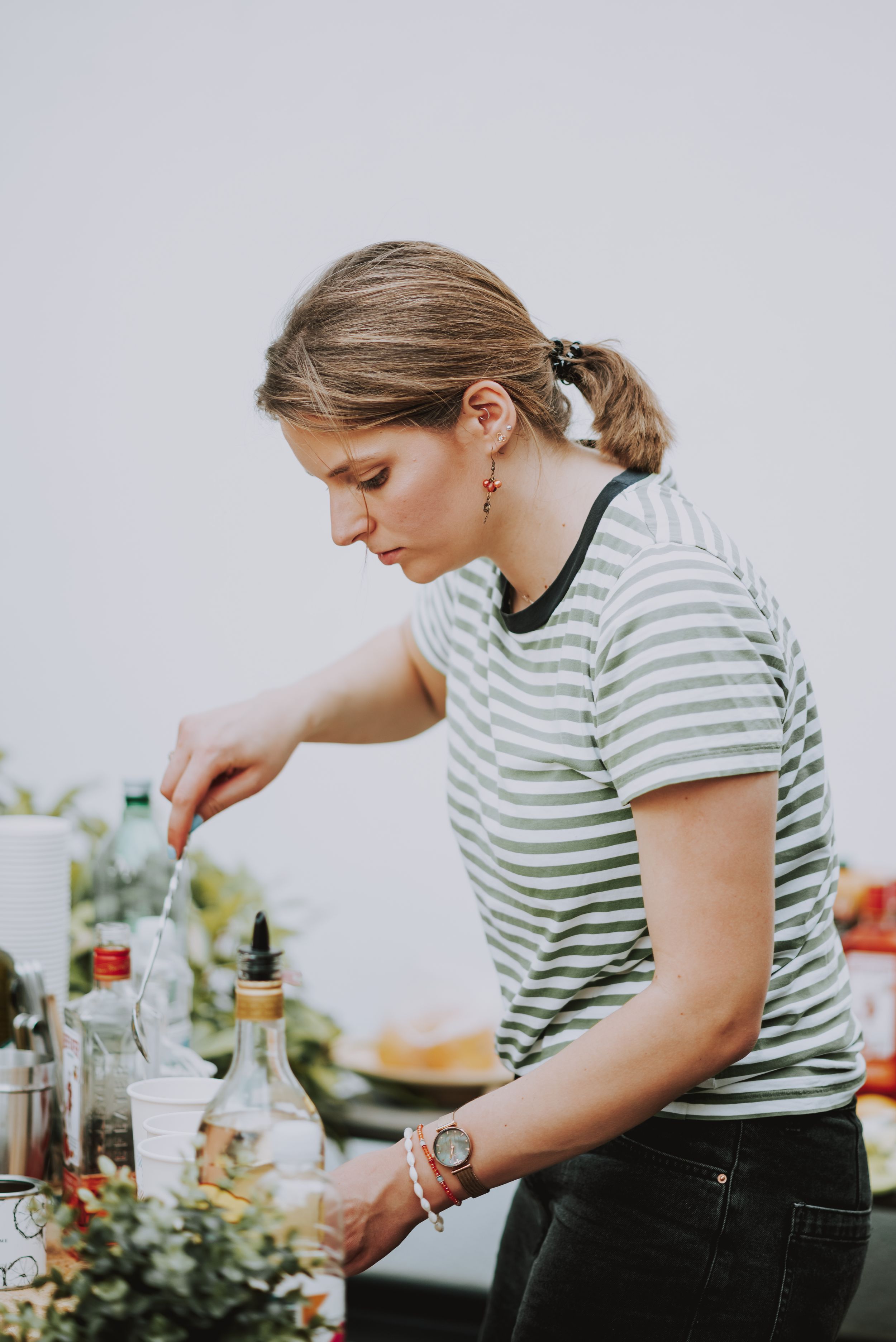 Person in striped shirt preparing drinks and appetizers at an event.