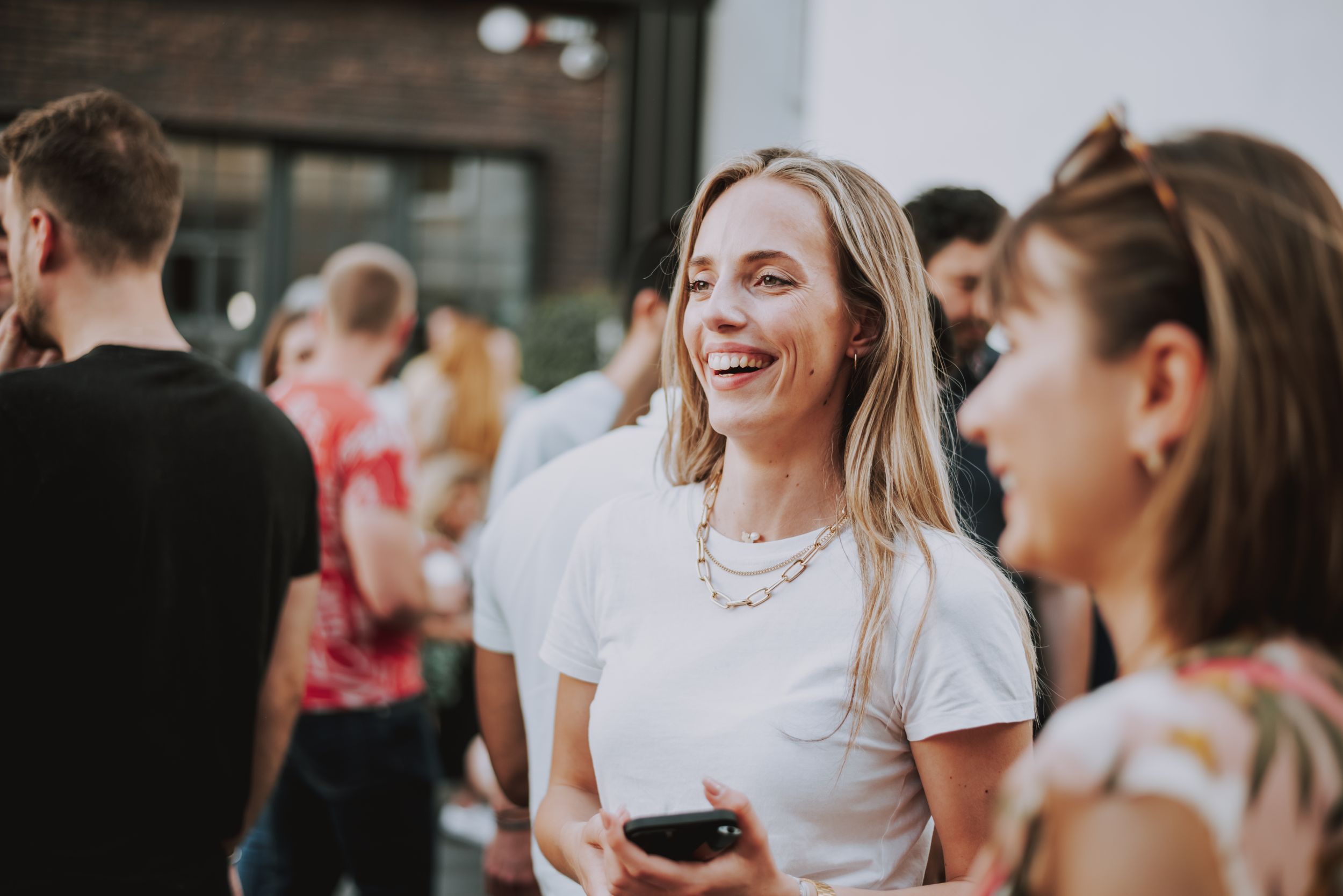 Group of people enjoying a social gathering outdoors with drinks and laughter.