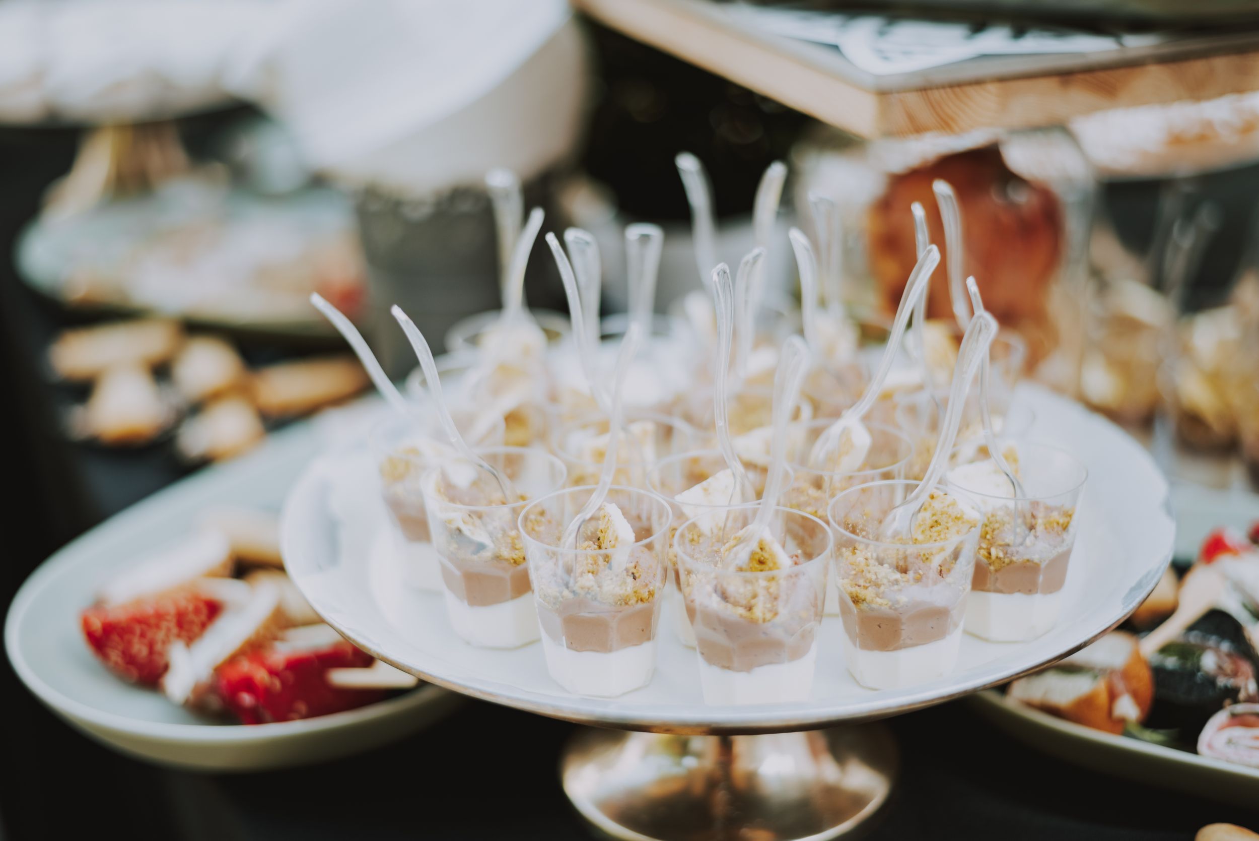 Appetizers and snacks served in individual clear cups on a white platter.