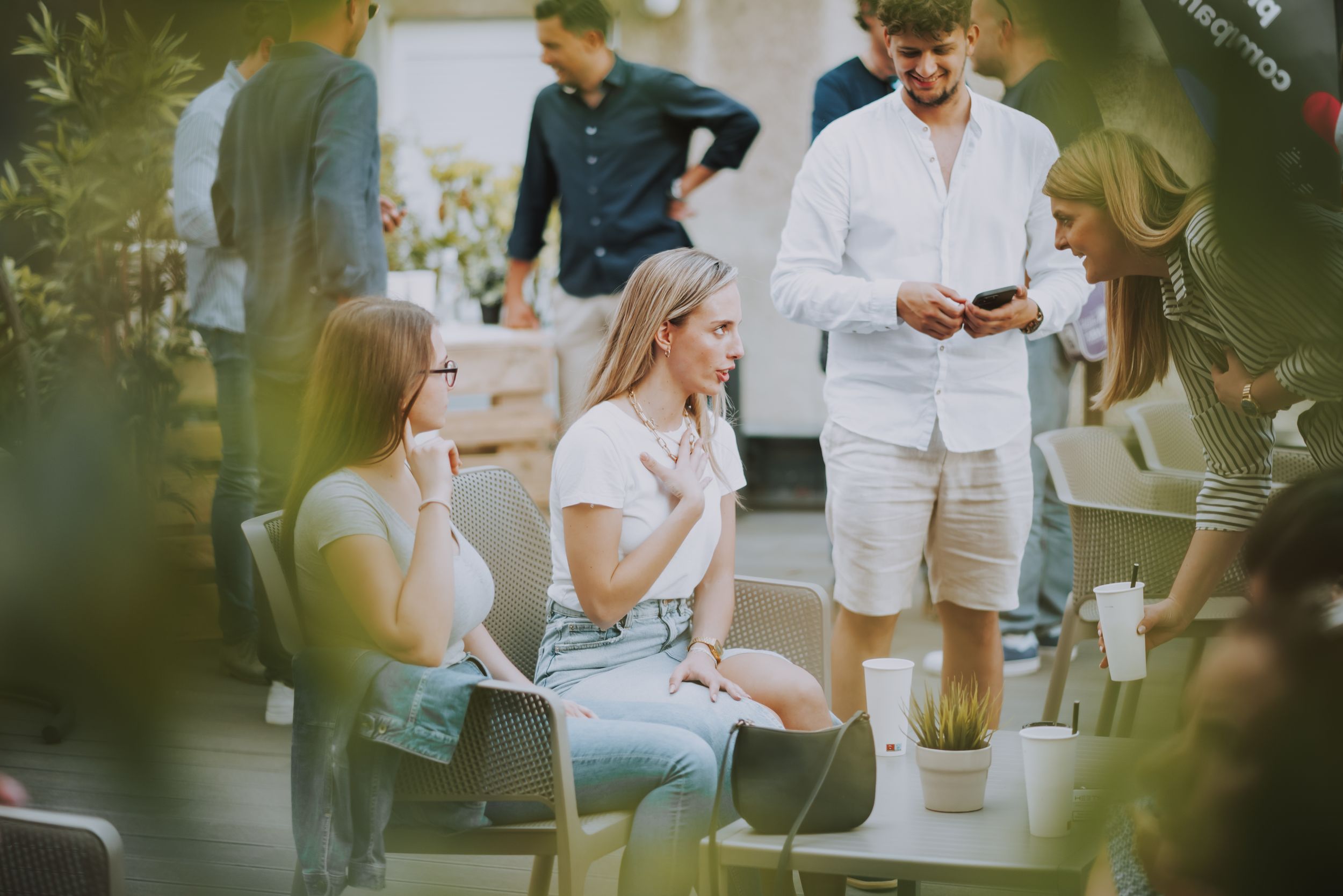 People enjoying a casual outdoor social gathering while seated in white chairs.