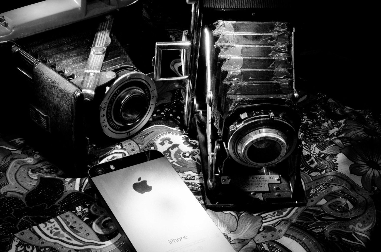 Black and White image of old camera and an Apple iPhone. Light painting.