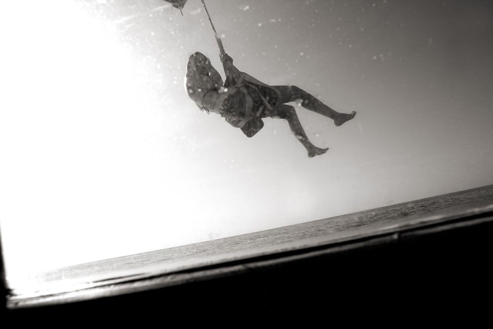 A dramatic black and white shot of a rock climber suspended in mid-air.