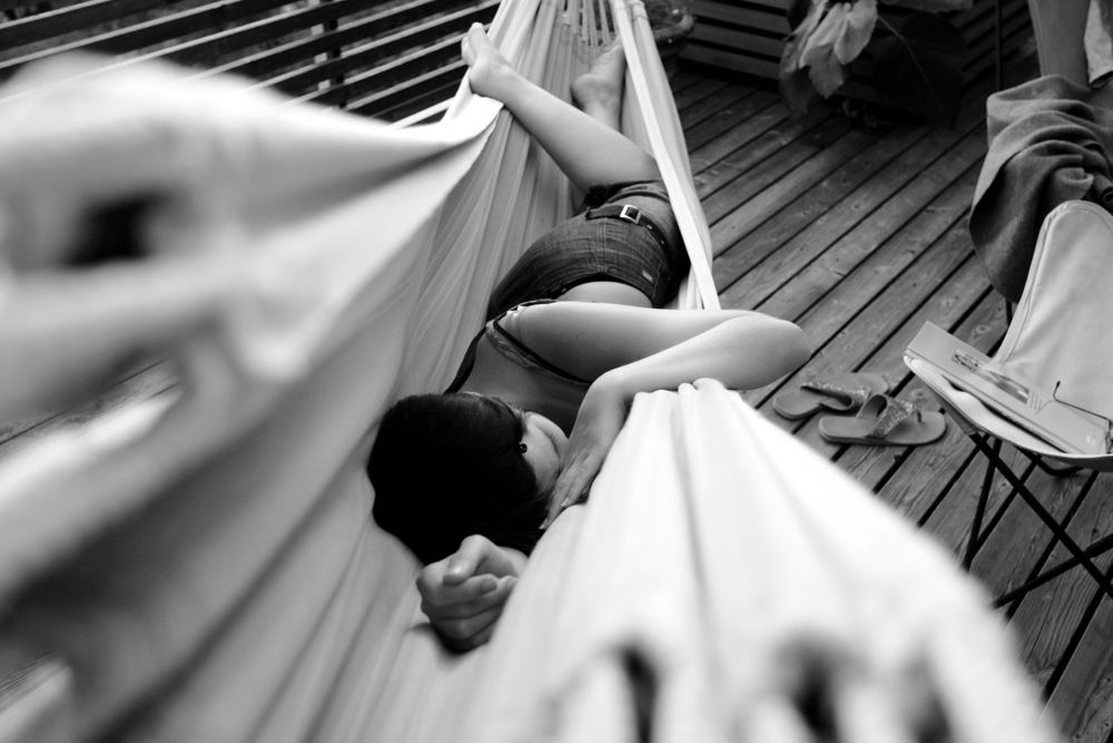 A black and white image of people relaxing under flowing fabric on a deck.
