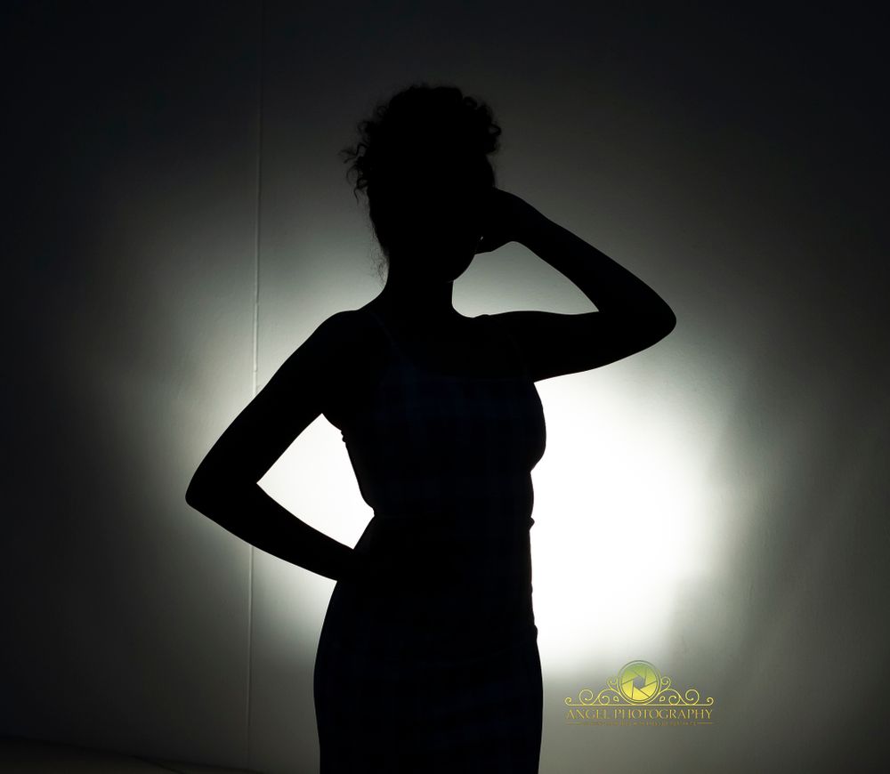 Artistic silhouette portrait against backlit background showing dramatic pose.