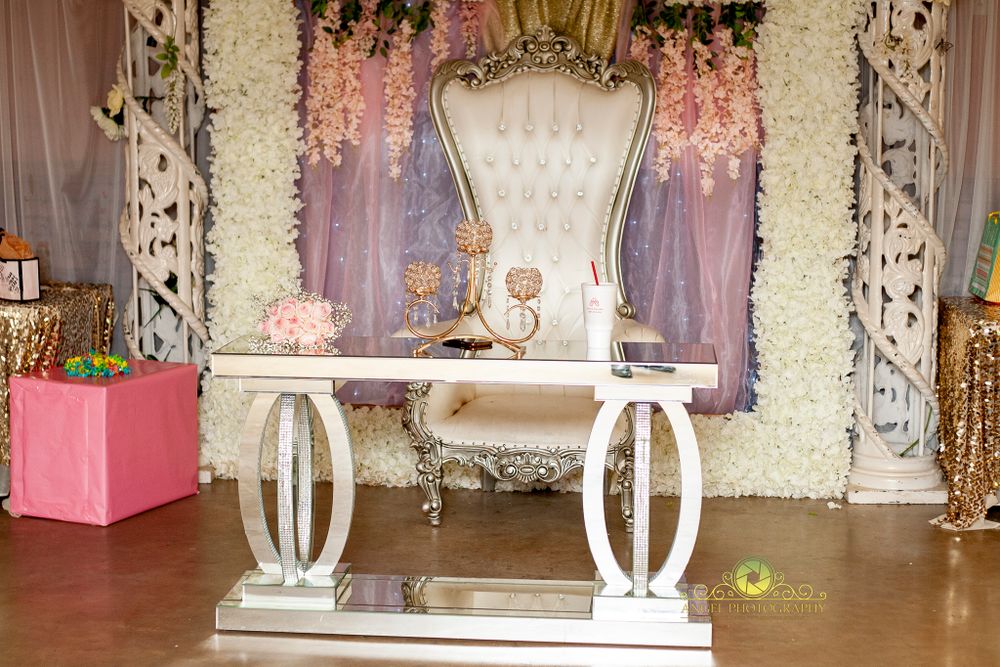Elegant white throne setup with floral arch and drapery for special event photography.