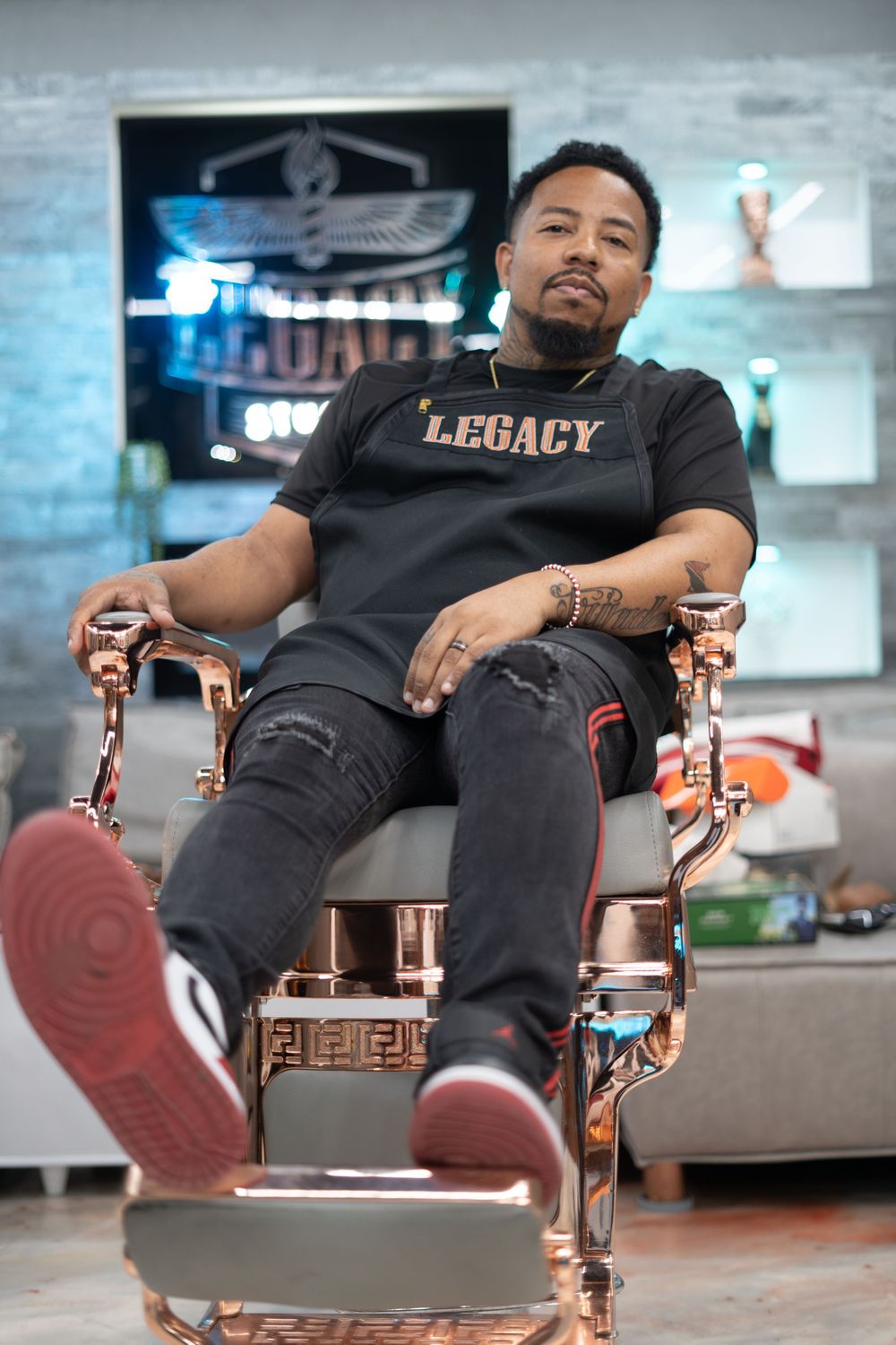 Person in black Legacy shirt relaxing in modern chair with legs extended.