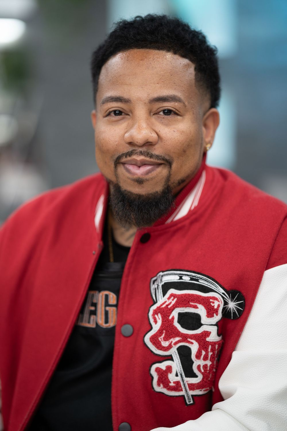 Portrait series showing person in red and white varsity jacket with friendly smile.