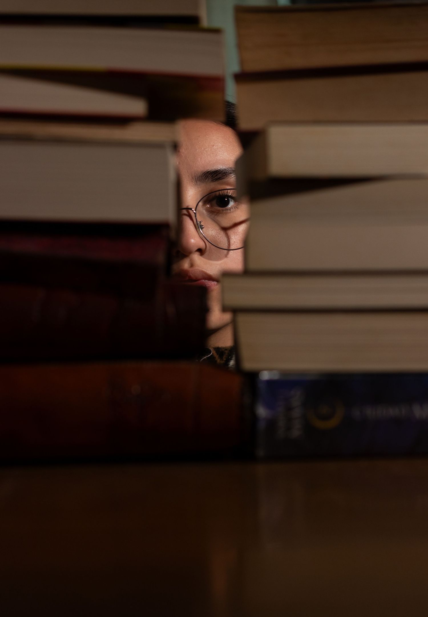 Close-up view of books on shelf with glasses peeking through.