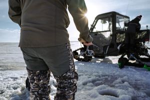 Ice fishermen set up their equipment on a frozen lake during a winter fishing expedition.