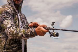 Fishing rod being cast over water during an outdoor fishing expedition.