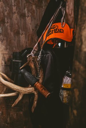Orange hunting gear and antlers displayed against a dark wooden background.