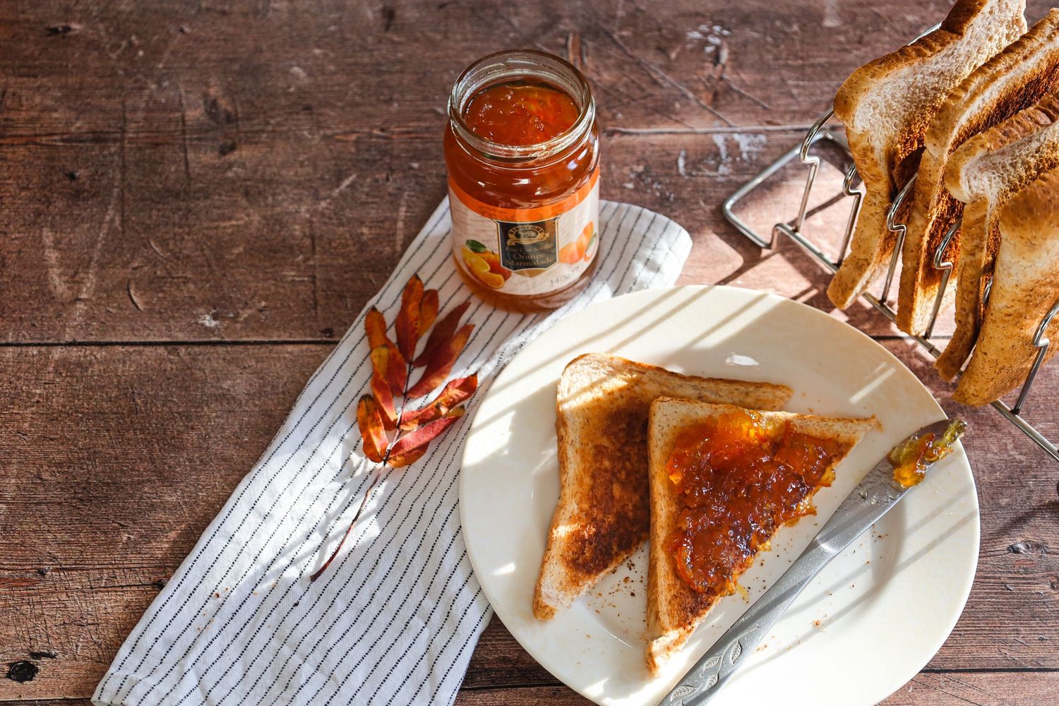 Sequence of toast being prepared on a rustic wooden table with spreads and jams.