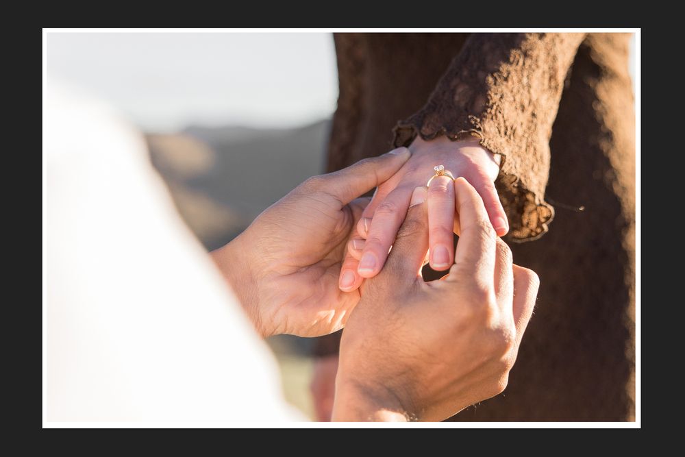 Close-up of couple exchanging wedding rings outdoors, symbolizing love and commitment during a romantic ceremony.