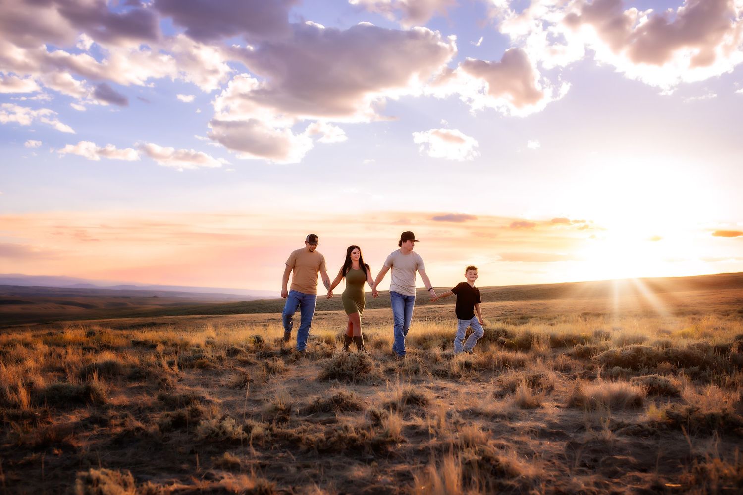 Extended family portrait in open field at sunset with grazing cattle in background.