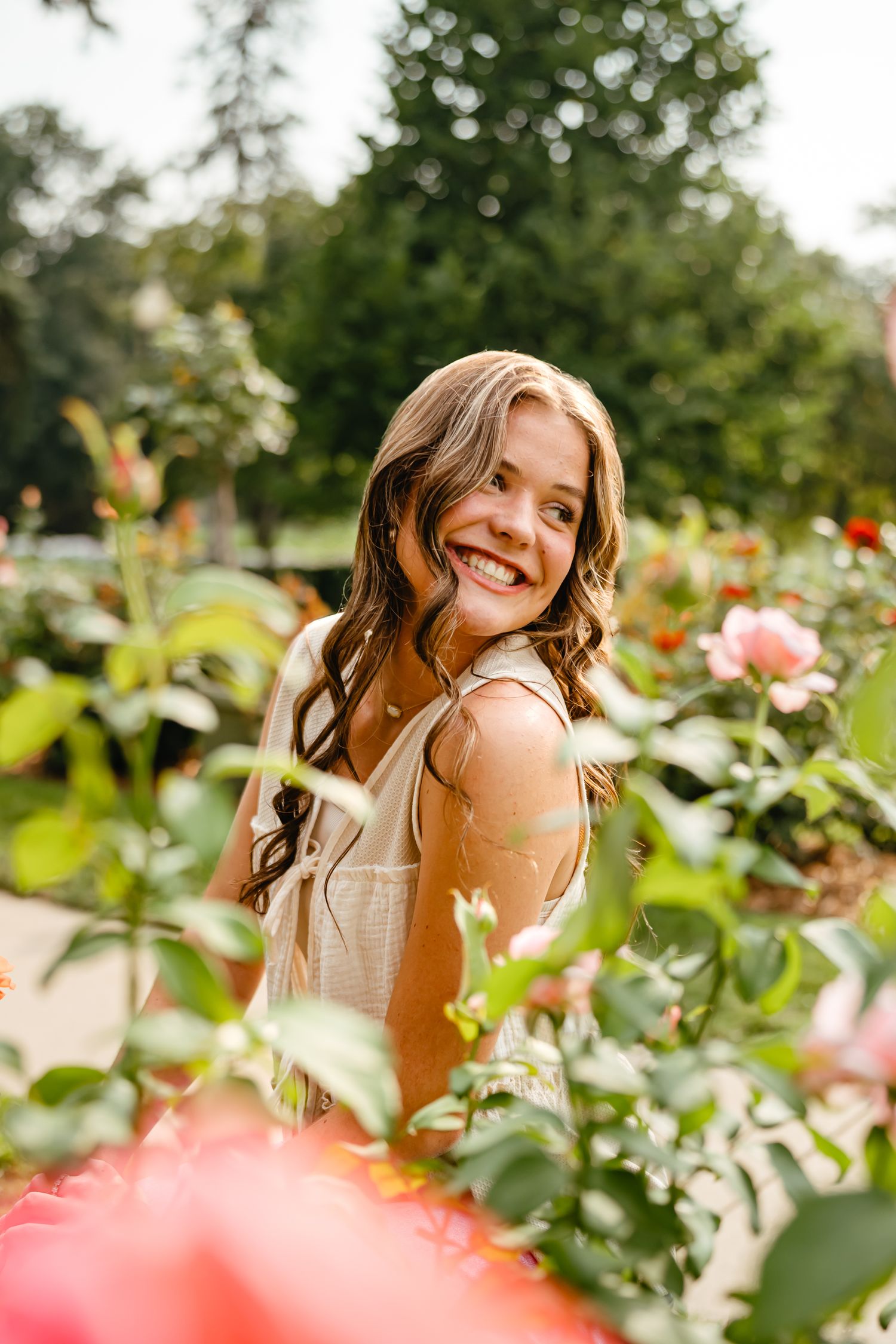 Woman posing playfully in a garden with blooming pink roses.