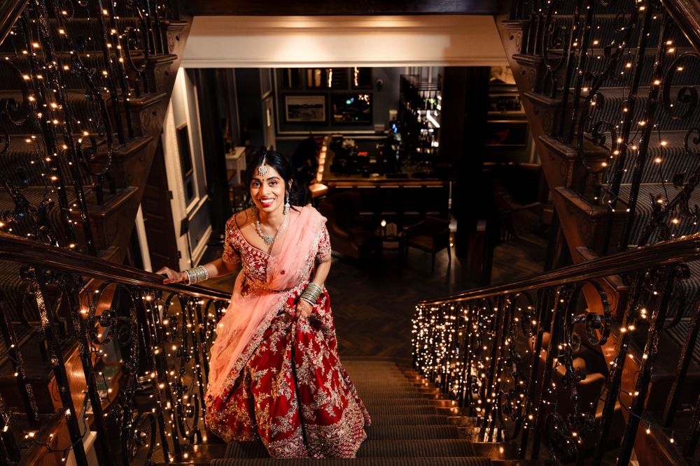 Person in red floral dress descends staircase decorated with twinkling fairy lights.