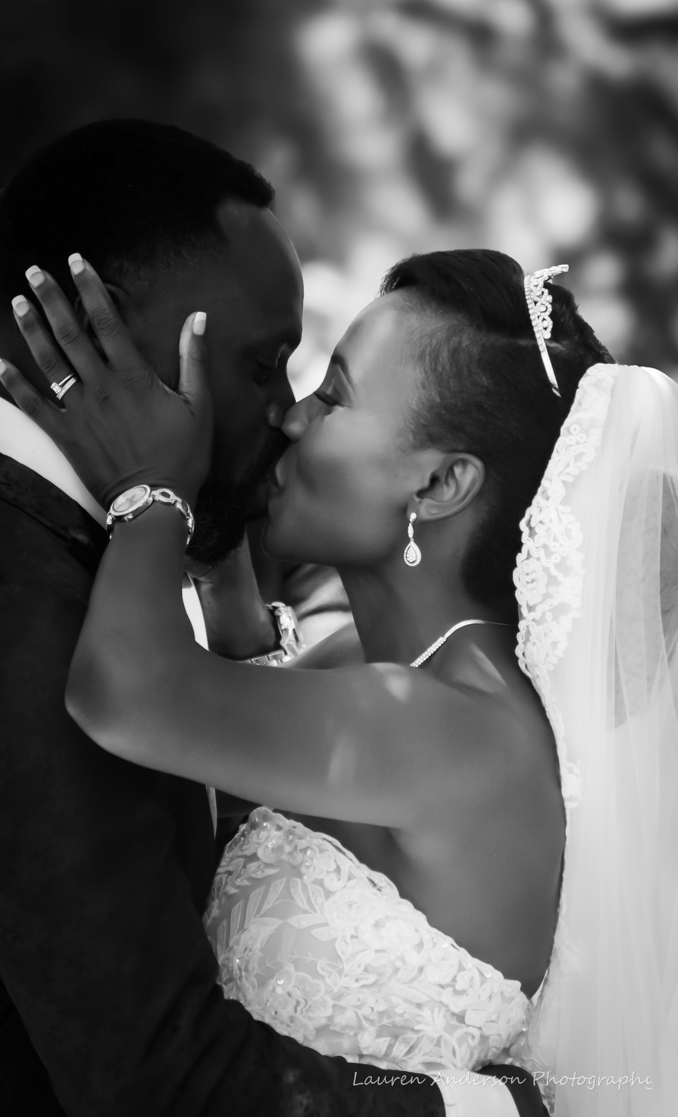 Black and white photo of a newlywed couple sharing a kiss, bride wearing veil and tiara.