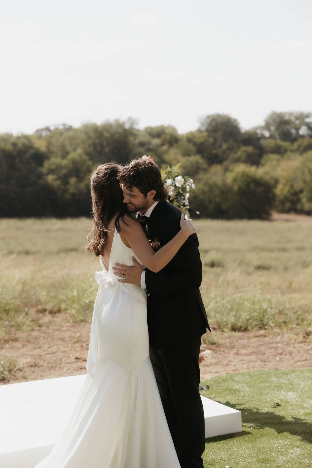 Bride and groom sharing a romantic first kiss at an outdoor wedding ceremony.